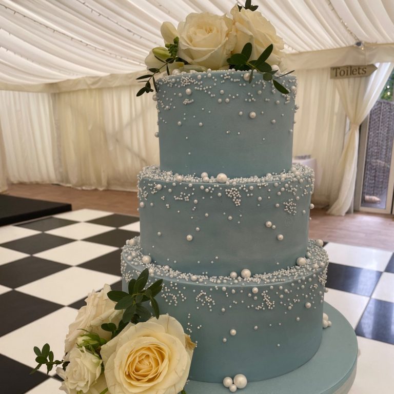 Elegant cascading pearls on pale blue three tier wedding cake