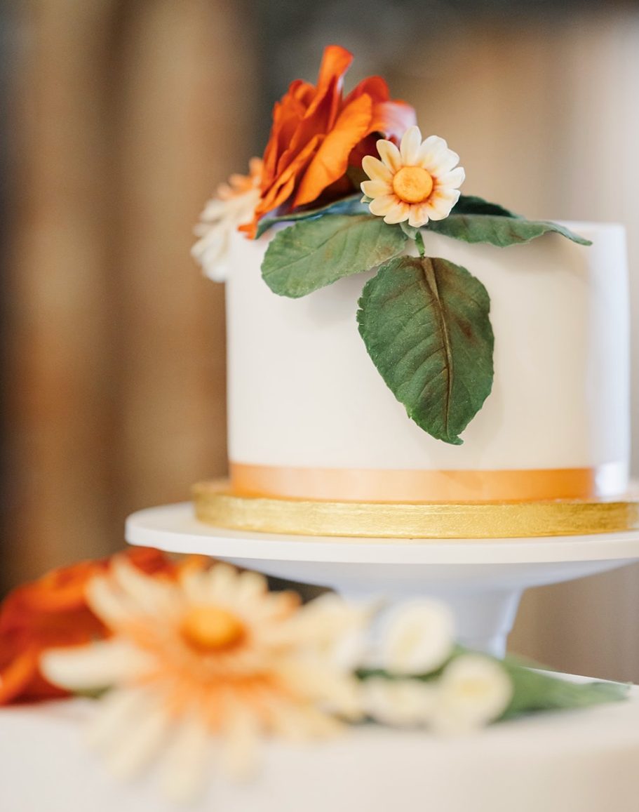 Wedding cake tier topped with finely made orange sugar flower rose Wedding cake tier topped with finely made orange sugar flower rose