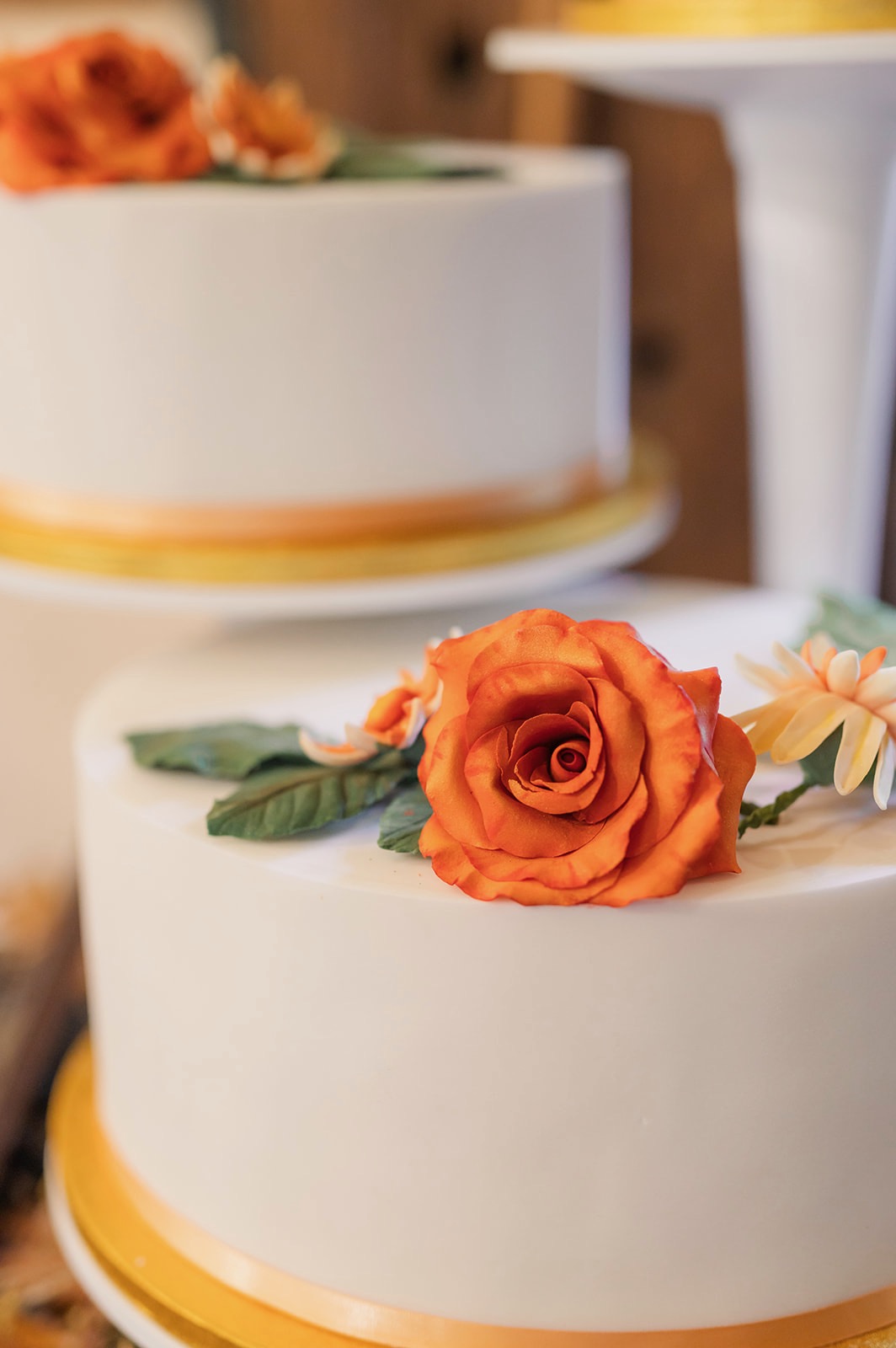 Two tier white wedding cake topped with amber colour hand crafter sugar paste roses