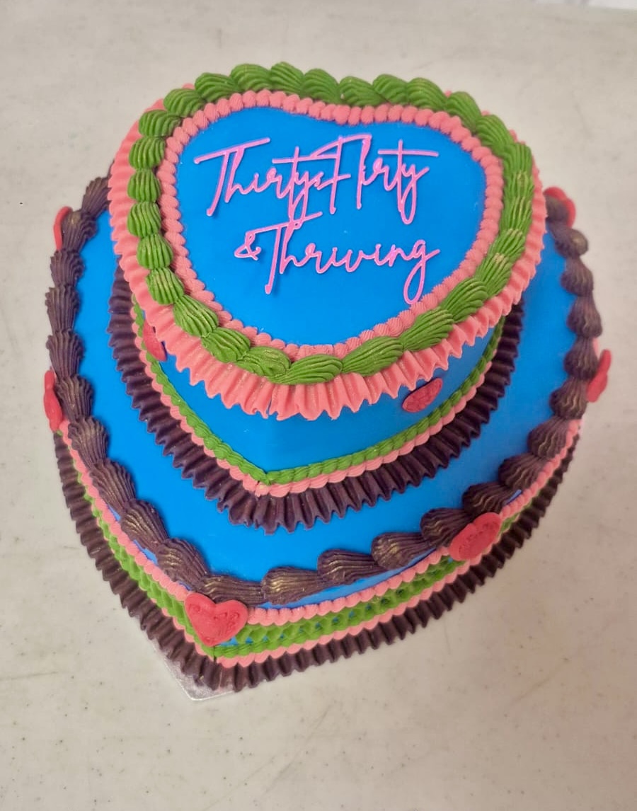 Thirty Flirty & Thriving Two tiered heart shaped cake with brightly coloured icing